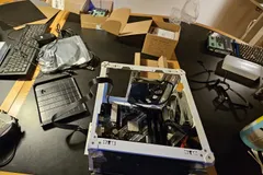 The server mid-build, with the case frame, motherboard, fans, and tools spread across the desk