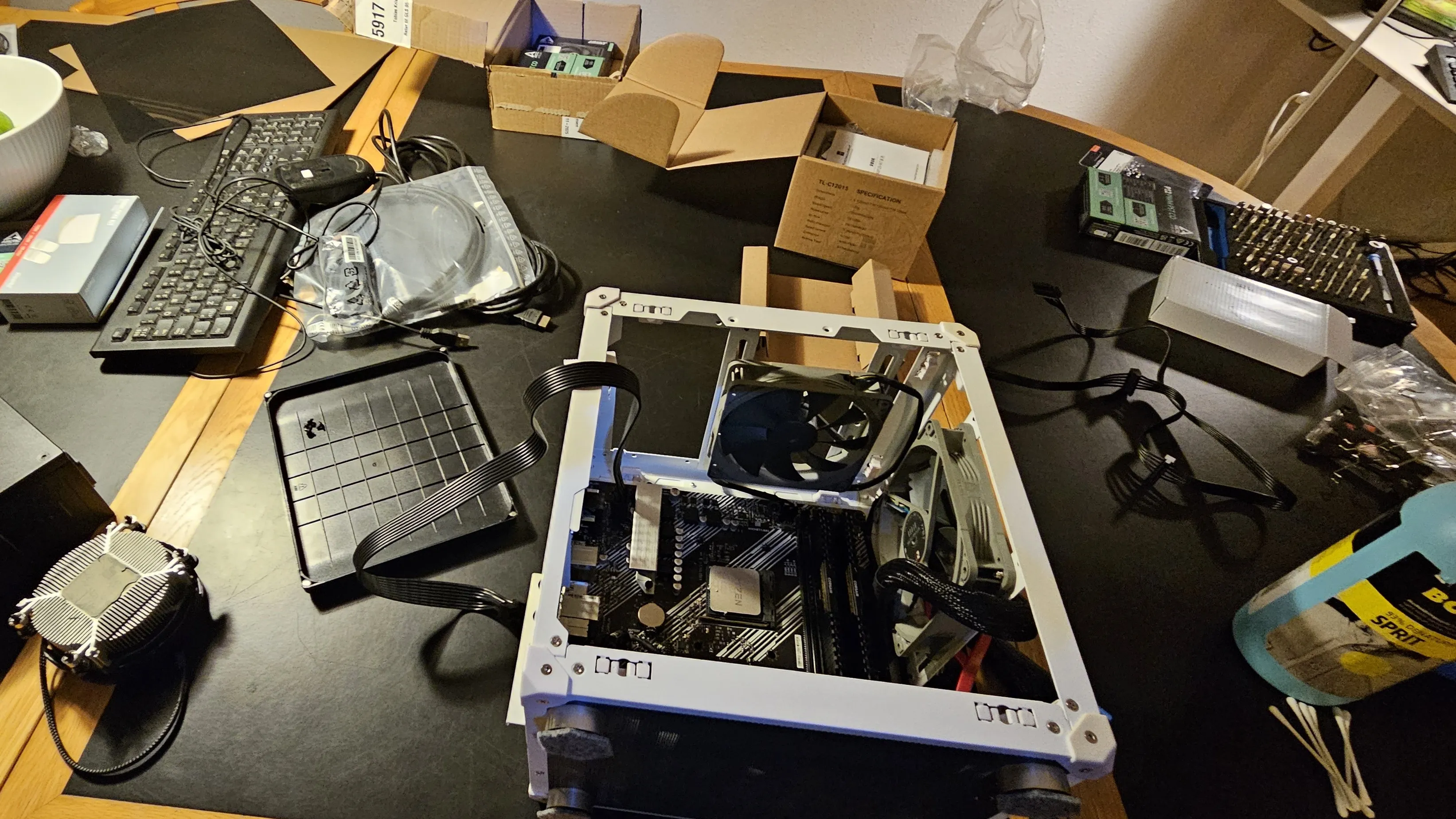 The server mid-build, with the case frame, motherboard, fans, and tools spread across the desk